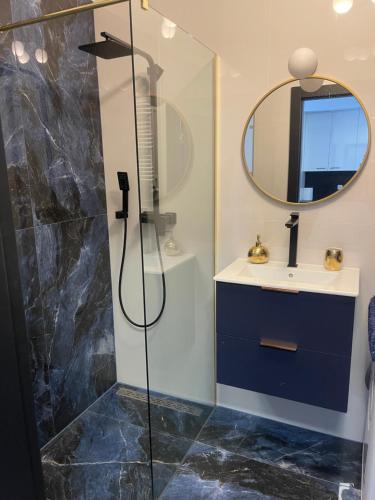 a bathroom with a shower and a sink and a mirror at Baltic Apartment in Gdańsk