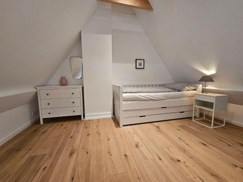 a bedroom with a bed and a dresser in a attic at Haus-Ruhe-unter-Reet in Schmiedendorf