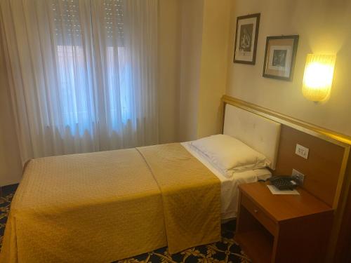 a hotel room with a bed and a table with a lamp at Hotel Milan Speranza Au Lac in Stresa