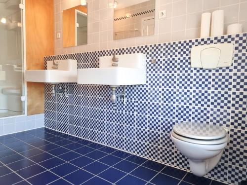 een badkamer met een wit toilet en een blauwe tegelvloer bij Ruim appartement Vlissingen VL23 in Vlissingen