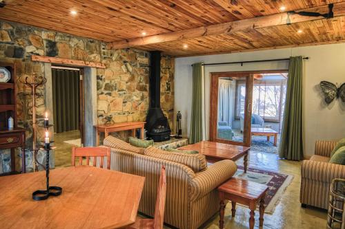 a living room with couches and a stone wall at Wetlands Country House & Sheds in Wakkerstroom