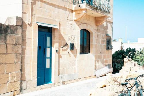 a building with a blue door on the side of it at Kampanjola in San Lawrenz