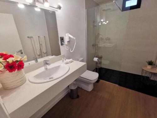 a bathroom with a sink and a toilet and a mirror at Chalé Esmeralda - Charming Studios in Calheta Beach in Calheta