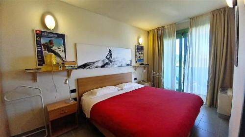 Habitación de hotel con cama roja y ventana en villaggio olimpico, en Sestriere