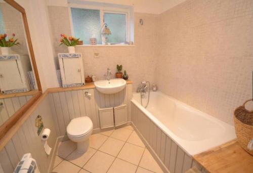 a bathroom with a toilet and a tub and a sink at Windsor Cottage in Milton Abbas