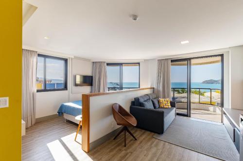 Habitación de hotel con cama y sofá en Aion Suítes - Exclusivo Loft, Praia de Bombinhas, en Bombinhas