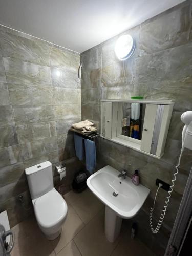 a bathroom with a white toilet and a sink at H&A Guest House in Divjakë