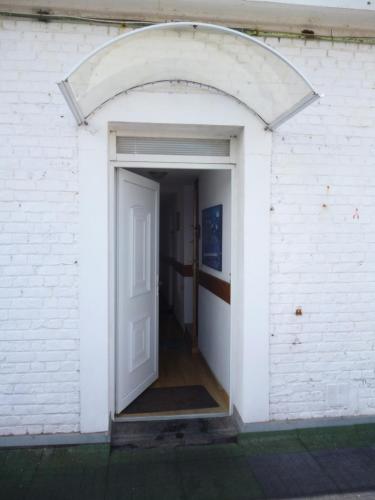 an entrance to a white brick building with an open door at Gentlemen appartement au premier étage à 50 metres de la mer in Sangatte