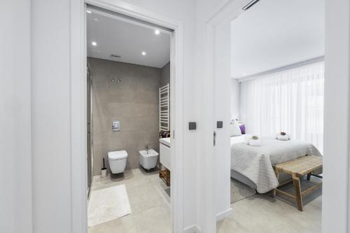 a white bedroom with a bed and a bathroom at Terracos de Quarteira II Purple by Real Properties in Quarteira
