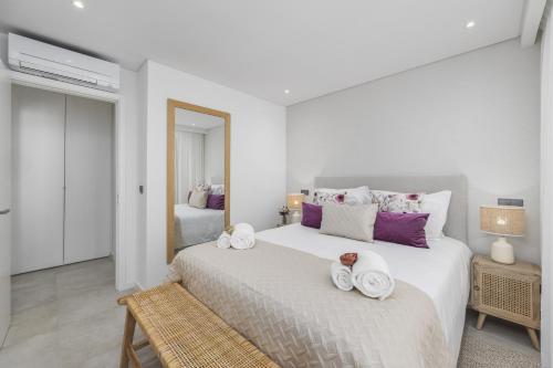 a white bedroom with a large bed with towels on it at Terracos de Quarteira II Purple by Real Properties in Quarteira