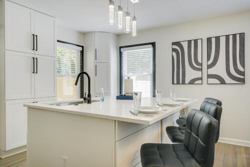 a kitchen with a large white island with black chairs at Modern Raleigh Vacation Rental about 3 Mi to Downtown! in Raleigh