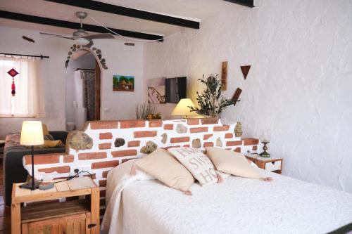 - une chambre avec un lit blanc et un mur en briques dans l'établissement Cuarto Teide Apartamento Santo Domingo, à La Guancha