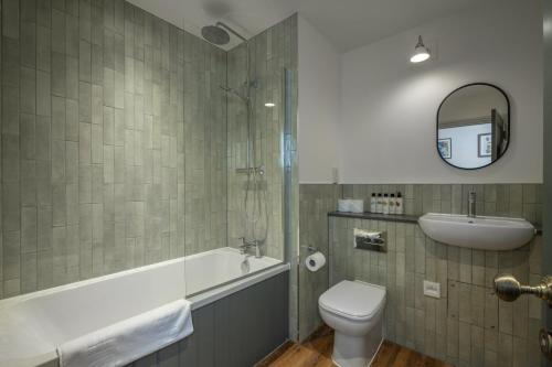 a bathroom with a tub and a toilet and a sink at The Railway Hotel Worthing in Worthing