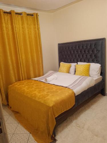 een slaapkamer met een bed met een geel gordijn bij Beautiful cosy one bedroom in Nairobi in Nairobi