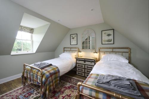 a attic bedroom with two beds and a window at Middleton Farmhouse in Inverness