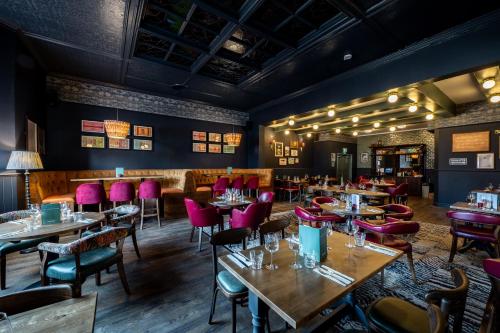 a restaurant with wooden tables and pink chairs at The Railway Hotel Worthing in Worthing