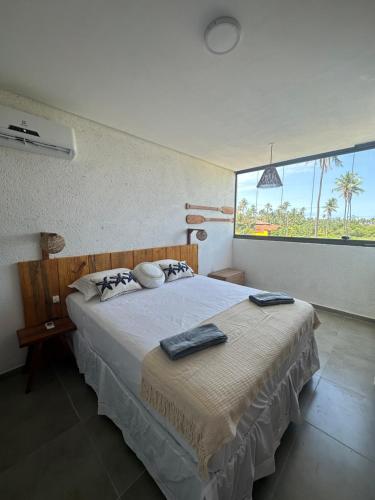 sypialnia z dużym łóżkiem i dużym oknem w obiekcie Casa Natture Patacho w mieście Pôrto de Pedras