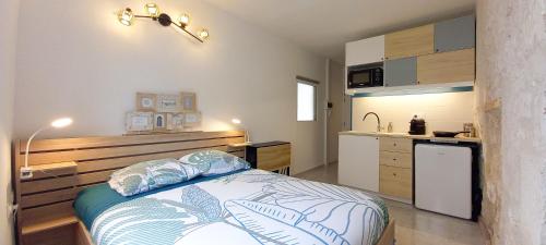 małą sypialnię z łóżkiem i kuchnią w obiekcie Studio sur chemin de Compostelle w mieście Port-de-Piles