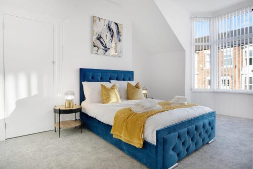 un letto blu in una camera bianca con finestra di Spacious & Modern Oasis, 4-Bed House, Sleeps 7 a Sunderland