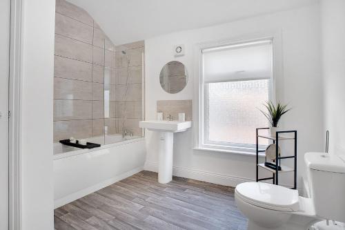 Baño blanco con lavabo y aseo en Spacious & Modern Oasis, 4-Bed House, Sleeps 7 en Sunderland