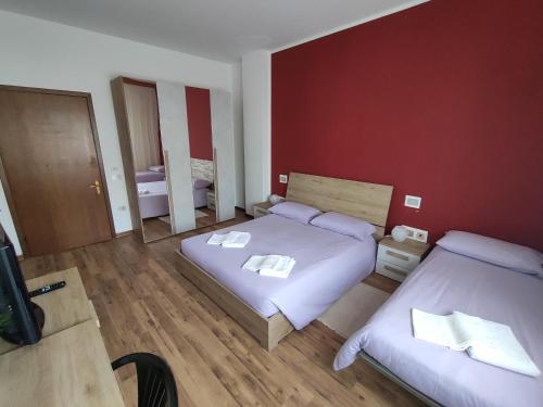 a bedroom with two beds and a red wall at Albergo Al Trieste in Nimis