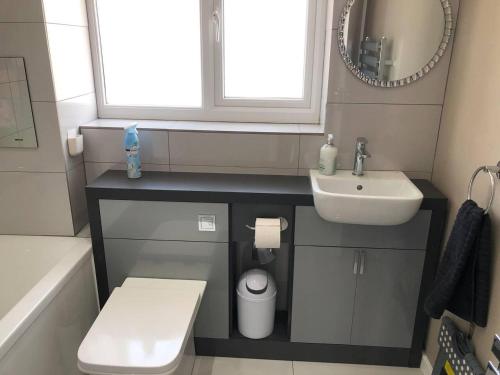 a bathroom with a sink and a toilet and a mirror at Luxury House in Camber Sand Beach is 2min Walk !! in Rye