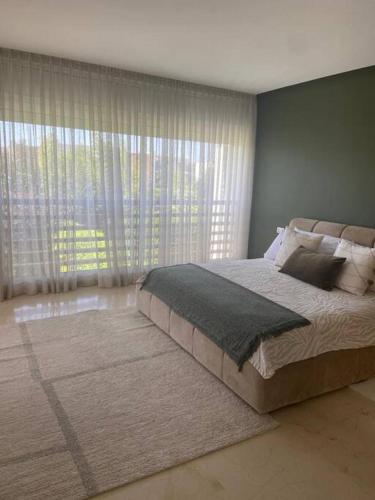 ein Schlafzimmer mit einem großen Bett und einem großen Fenster in der Unterkunft Maison entière Securisée à Casa Green Town in Casablanca