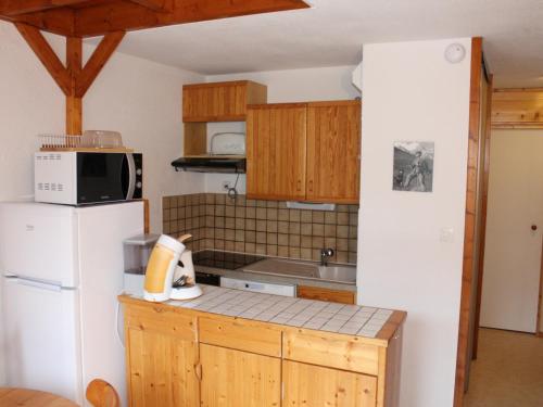 La cuisine est équipée d'un réfrigérateur blanc et de placards en bois. dans l'établissement Duplex 3* au centre de Valloire, proche télécabine, 6 pers, balcon - FR-1-263-423, à Valloire