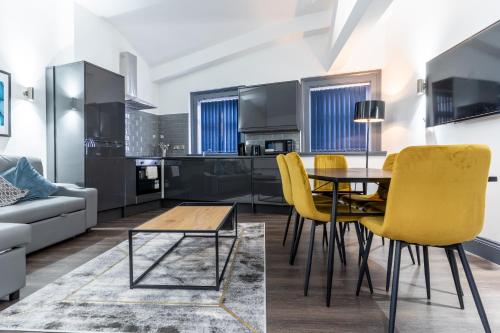 a living room with a table and yellow chairs at Temple Court by UStay Aparthotels in Liverpool
