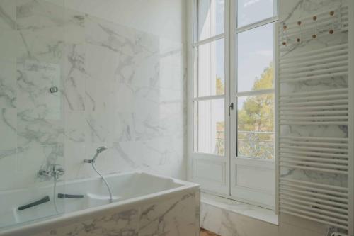 La salle de bains blanche est pourvue d'une baignoire et d'une fenêtre. dans l'établissement Château de Bayssan, à Béziers