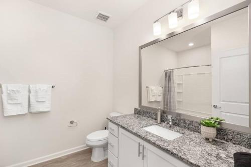 ein Badezimmer mit einem Waschbecken, einem WC und einem Spiegel in der Unterkunft Modern Smart Apt Near Charlotte in Concord