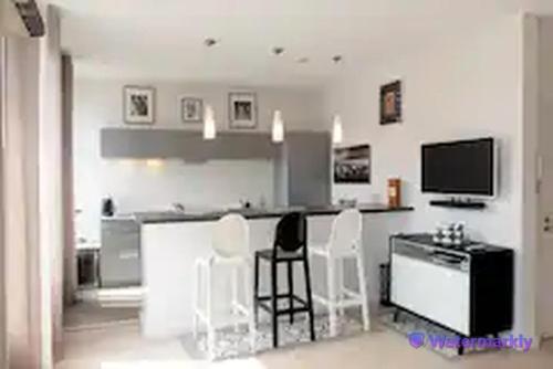 a kitchen with white chairs and a bar with a tv at La Suite - T2 Prestige - Hypercentre in Albi