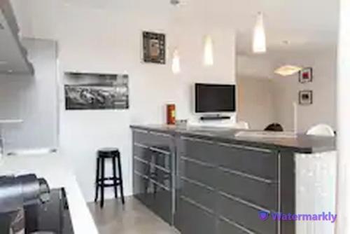 a kitchen with a counter with a television and a stool at La Suite - T2 Prestige - Hypercentre in Albi