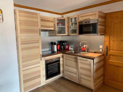 Elle comprend une petite cuisine avec des placards en bois et un évier. dans l'établissement Appartement 3 pièces 6 pers avec balcon, accès piscine, à 700m du centre de Valloire. - FR-1-263-437, à Valloire