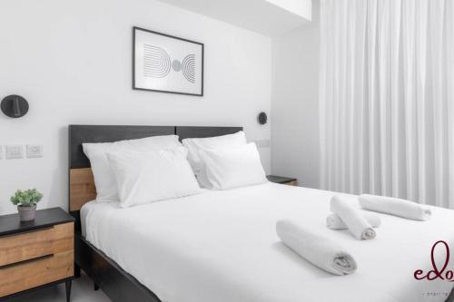 una camera da letto con un letto bianco con due asciugamani di דירה משפחתית מרווחת 50 מטר מהים - By Edom a Eilat
