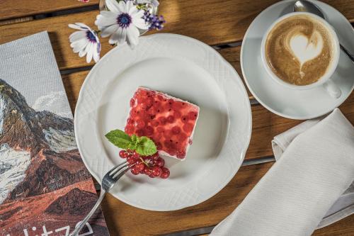 a piece of cake on a plate with a cup of coffee at Biohotel Rastbichlhof in Neustift im Stubaital
