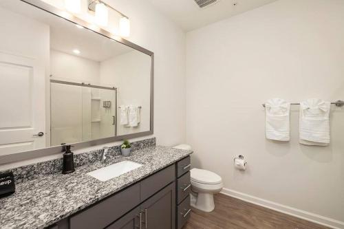 y baño con lavabo, aseo y espejo. en Cozy Modern Condo Near Charlotte, en Concord