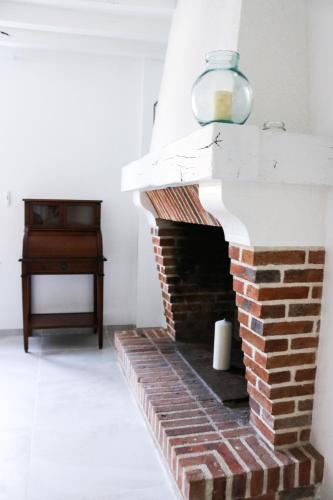 a brick fireplace in a living room with a lamp at L'hermine de Sologne in Courmemin