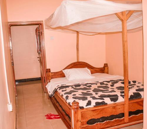1 dormitorio con cama de madera y dosel en CAJANUS RESORT KARATU, en Karatu