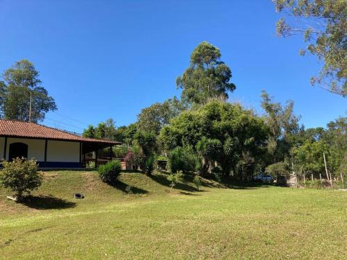 une cour avec une maison et des arbres en arrière-plan dans l'établissement Casa de campo com piscina a 2 min de cunha, à Cunha