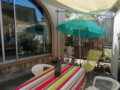 Una mesa y sillas con una sombrilla en un patio. en Studio bord de mer équipé air conditionné 1min de la plage, en Lumio
