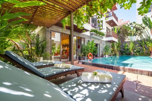 un patio al aire libre con piscina y tumbonas en December Hoi An Villa en Hoi An
