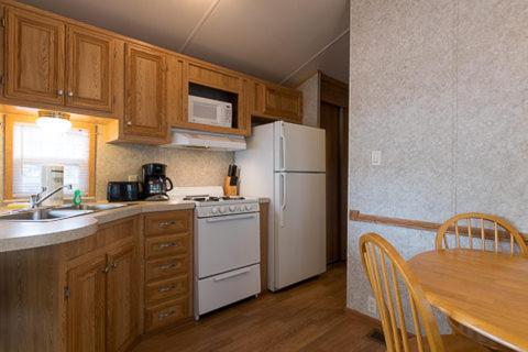 a kitchen with a white refrigerator and a table at Point Sebago Resort in Casco