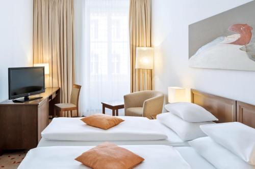 um quarto de hotel com duas camas e uma televisão em Hotel Rathauspark Wien, a member of Radisson Individuals em Viena