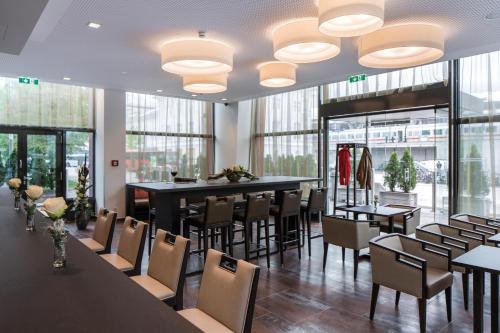 فندق تريند النمسا أوروبا سالزبورغ في سالزبورغ: غرفة طعام مع طاولات وكراسي ونوافذ