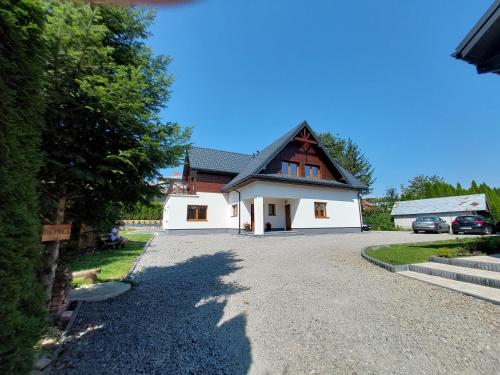a large white house with a driveway at Agroturystyka Bliżej Natury in Rymanów-Zdrój