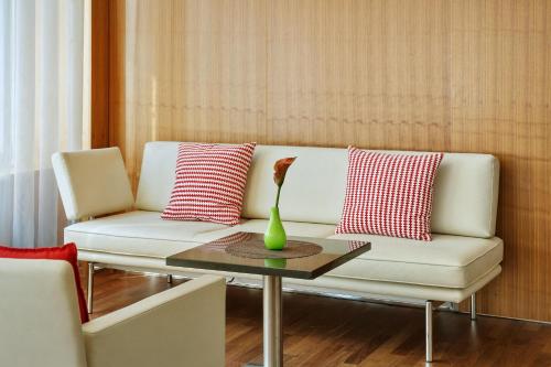 a white couch with red and white pillows and a table at Austria Trend Hotel Europa Wien in Vienna