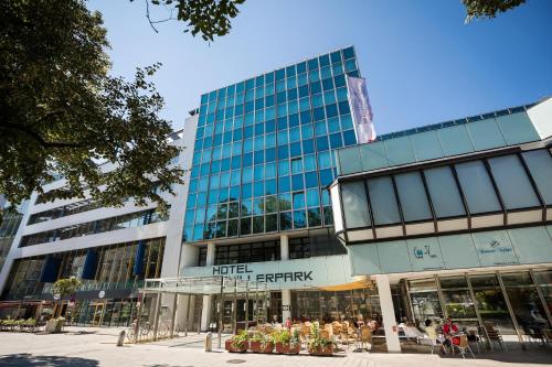 ein großes Glasgebäude mit Leuten, die draußen sitzen in der Unterkunft Hotel Schillerpark Linz, a member of Radisson Individuals in Linz