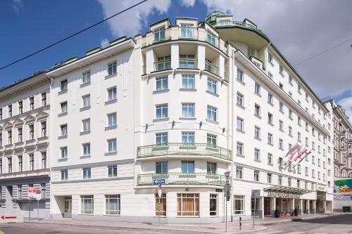 a large white building on the corner of a street at Austria Trend Hotel Ananas Wien in Vienna