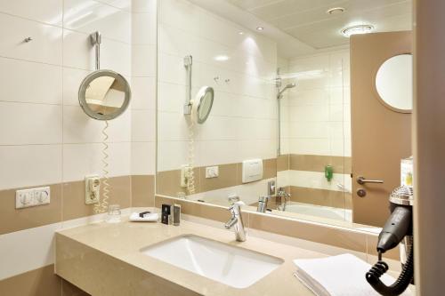a bathroom with a sink and a mirror at Hotel Schillerpark Linz, a member of Radisson Individuals in Linz